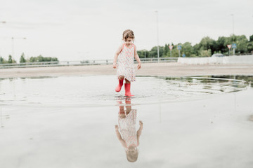 Little girl playing in a puddle, happy. stock photo