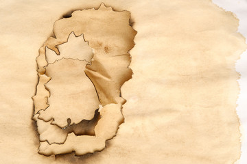 Aged paper layers with burnt edges on beige stained background. Grunge abstract design. Copy space.