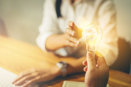 Sharing an idea concept, hand sharing a light bulb of idea to businesswoman