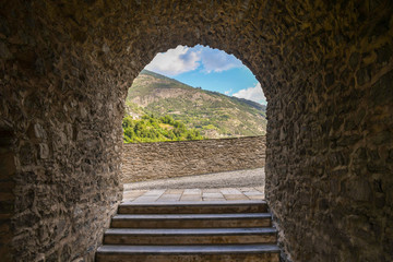 Obraz premium An old stone arcade with a staircase and a view on the slope of a mountain in summer, Aosta Valley, Italy