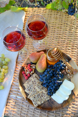 Autumn picnic in the garden Wine glasses and wine snacks on a wicker table outdoor Lunch in nature