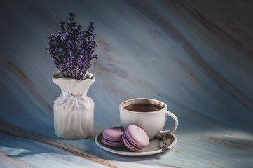 Cup of tea with lavender macarons on texture background. French delicate dessert. Minimalism, soft focus, copy space. Toned background. Good morning concept.