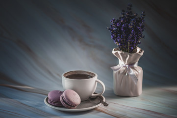 Cup of tea with lavender macarons on texture background. French delicate dessert. Minimalism, soft focus, copy space. Toned background. Good morning concept.