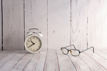 white vintage alarm clock and glasses