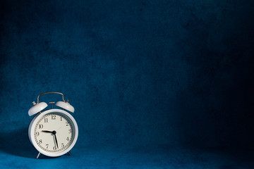 white vintage alarm clock on abstrac blue
