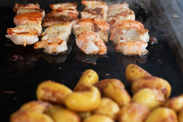 Shrimps sea food and potatoes on black roasted pan background