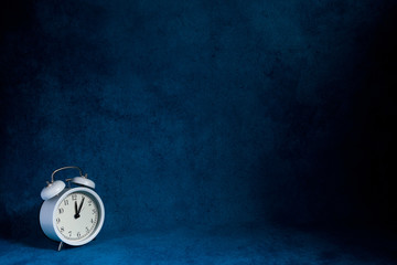 white vintage alarm clock on abstrac blue background