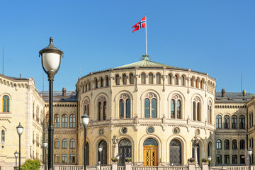 Fototapeta na wymiar Oslo, Norway. Parliament (The Storting building or Stortingsbygningen) with Norwegian flag in central Oslo. The building is built in yellow brick.