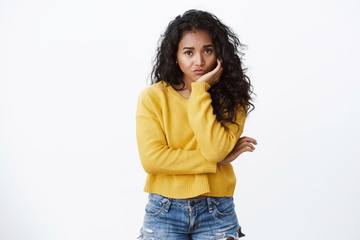 Uneasy and sad cute african american curly-haired girl in yellow sweater feeling lonely and bored,...