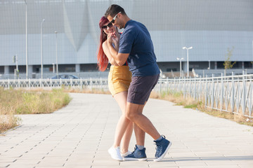 Young couple dancing Latino dance against urban landscape.