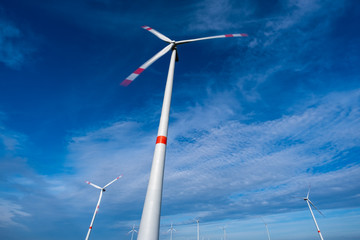 Windkraftanlage mit Langzeitbelichtung, leicht bewölkter blauer Himmel im Hintergrund