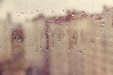 Fototapeta premium Hand drawn shape for text with flowing drops of water on muddy glass wet window in city