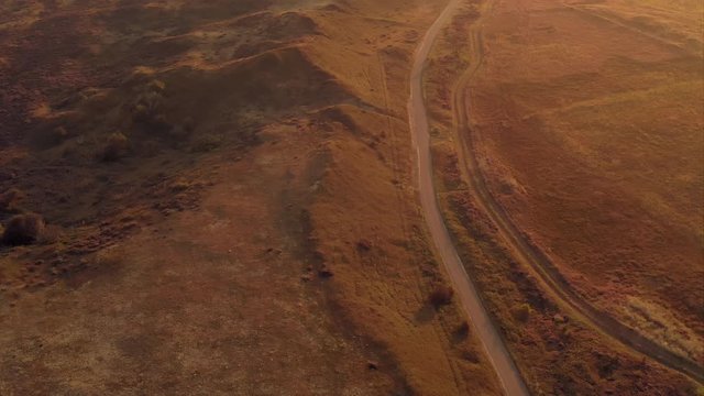 Aerial reveal shot of a unique sand dune landscape of Texel island in the Netherlands, shot during golden hour after sunrise 