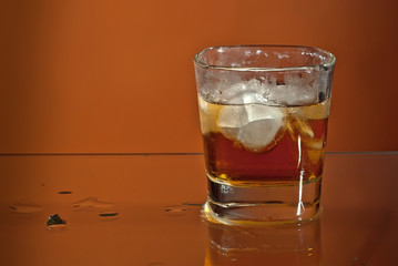 Alcoholic drink with ice in transparent glasses. Wine glass with cocktail isolated on orange background. Frozen drinks on glass table.
