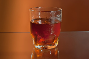 Alcoholic drink with ice in transparent glasses. Wine glass with cocktail isolated on orange background. Frozen drinks on glass table.