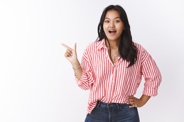 Girl gossiping about coworker pointing left astonished and speechless drop jaw from amazement and...