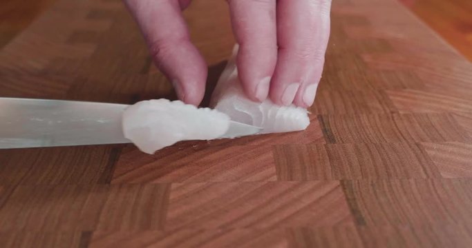 Sushi cuts thin slices of white fleshy snapper with a very sharp knife for Japanese sashimi and sushi. The fish is raw and white in color