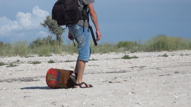A man walks past a rusty iron can on the Black Sea coastline