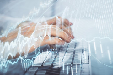 Multi exposure of graph with man typing on computer in office on background. Concept of hard work. Closeup.