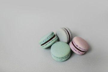 Overview of sweet macaroon biscuits of pastel color lying on light grey background. Copy space.