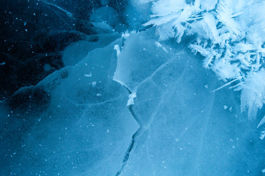 Winter ice background with snow and snowflakes. Natural texture of frozen water. New Year and Christmas card.