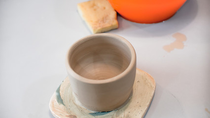 A raw clay pot in the hands of a potter. Workshop in the pottery workshop. Clay pot on a potter`s wheel