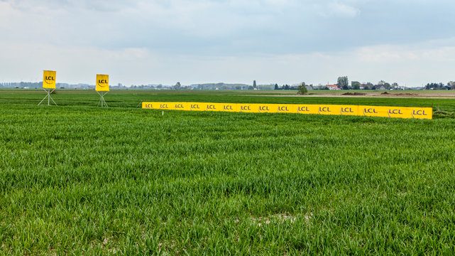Camphin-en-Pevele,France-April 13,2014:Yellows banners of the LCL Bank on the roadside of a cobblestone road in the field during Paris-Roubaix cycling race.