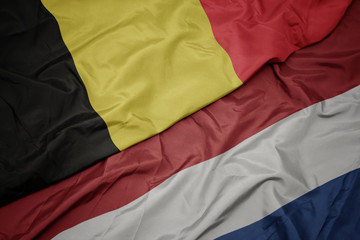 waving colorful flag of netherlands and national flag of belgium.