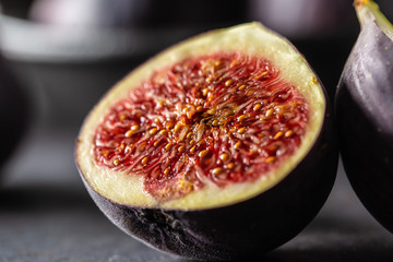 A few figs in a black bowl on an dark concrete table