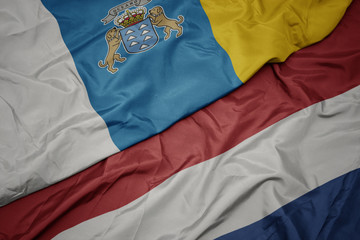 waving colorful flag of netherlands and national flag of canary islands.