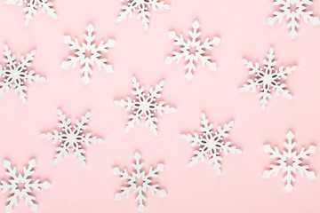 Christmas background. White snow decorations on a pink background.