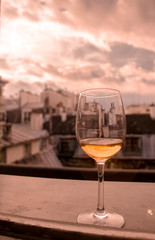 Glass of white wine on window sill with view of Paris roof tops