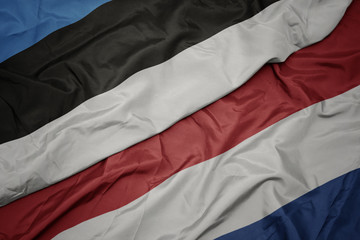 waving colorful flag of netherlands and national flag of estonia.