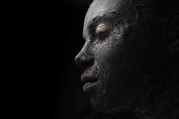 profile portrait of a woman with cracked black clay