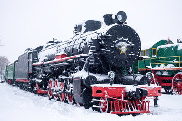 Fototapeta premium Steam train in snow. Soviet black and red locomotive. Steam engine transport.