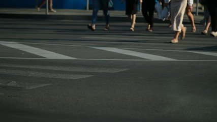 A lot of people are crossing the street at a crosswalk. feet closeup