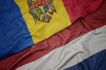 waving colorful flag of netherlands and national flag of moldova.