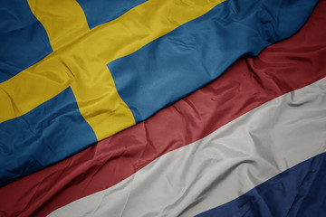waving colorful flag of netherlands and national flag of sweden.