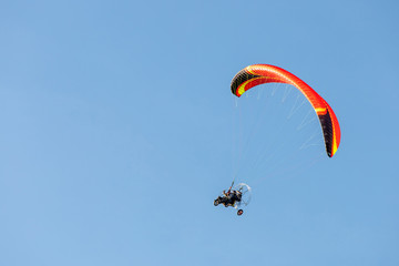 bright paraglider with a motor flies in the blue sky
