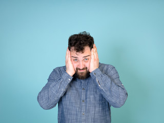 cool and young man with black hair and black beard posing in front of blue background doing different body exprssions with copy space and is happy