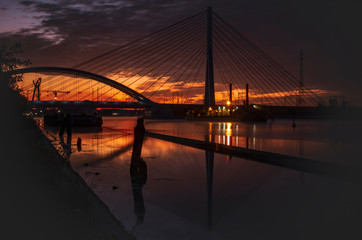 Panele Szklane  Wschód słońca nad rzeką, krajobraz miejski, mosty. 