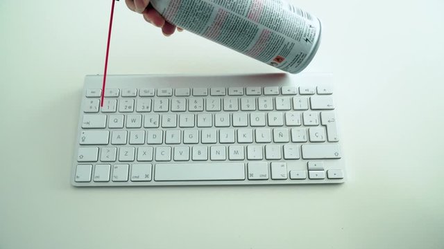 Dusting white keyboard with compressed air spray, White Background