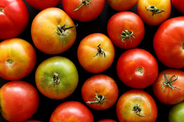 Fresh organic tomatoes  on a black background, close-up, top view