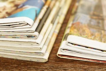 Pile of fresh morning newspapers on the table at office. Latest financial and business news in daily paper. Pages with information (headlines, articles, photos, text). Folded and stacked journals