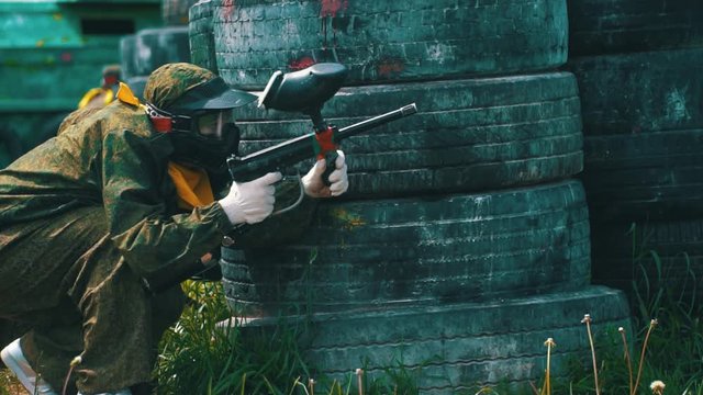 guy in camouflage with mask shoots with paintball gun