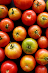 Fresh organic tomatoes  on a black background, close-up, top view