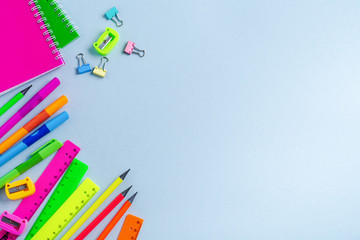 Notebook, colored pencils, ruler, pen, eraser, sharpener and more. School and office stationery on blue background. Concept back to school. Top view.