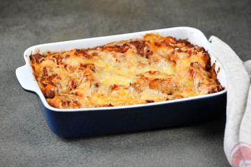 A dish of lasagna. Close-up. Dark background.