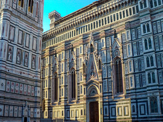 Florence Cathedral, Italy. Basilica of Santa Maria del Fiore (Duomo di Firenze) and bell tower (Giotto's Campanile) on the piazza del Duomo. Ornate marble facade of building exterior.