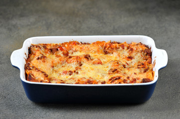 A dish of lasagna. Close-up. Dark background.